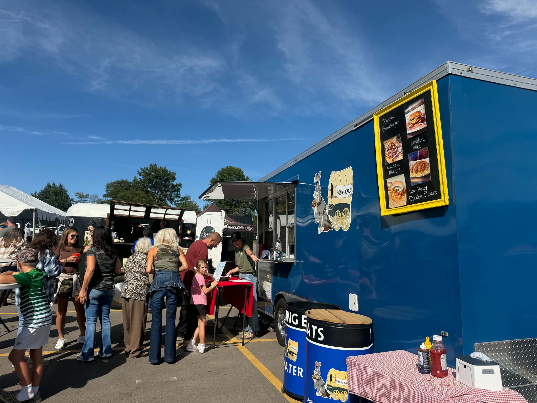 Crowd gathered at the Hauling Eats trailer under a bright blue sky