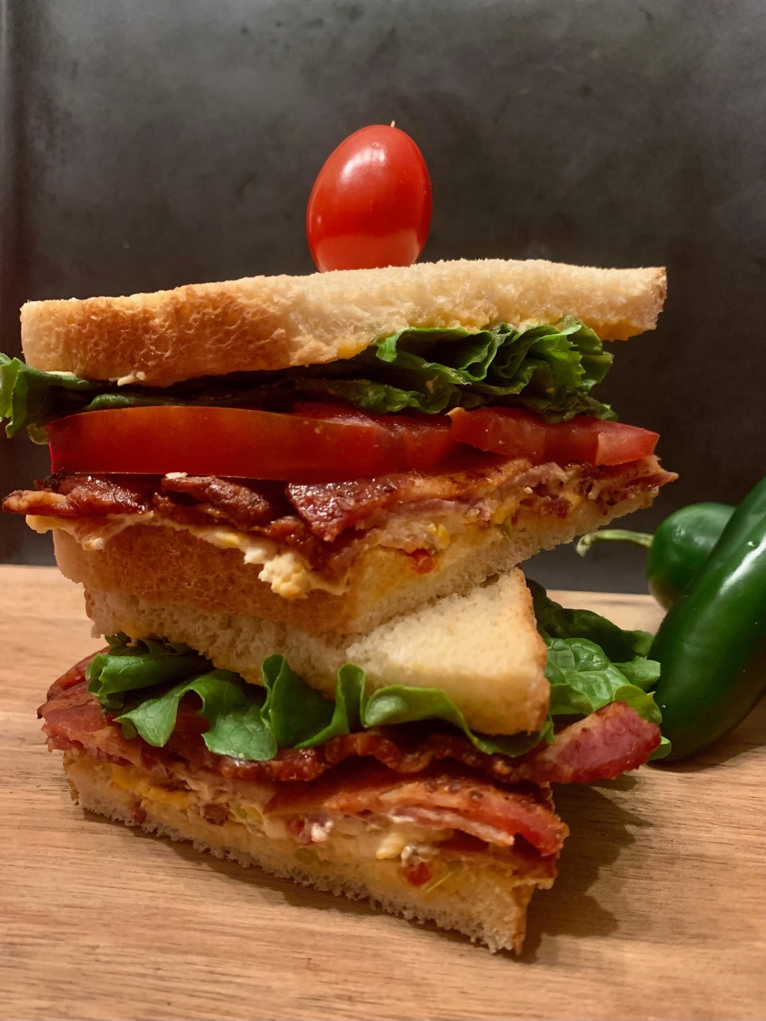 Stacked BLT sandwich with crisp bacon, tomato, lettuce, and a jalapeño