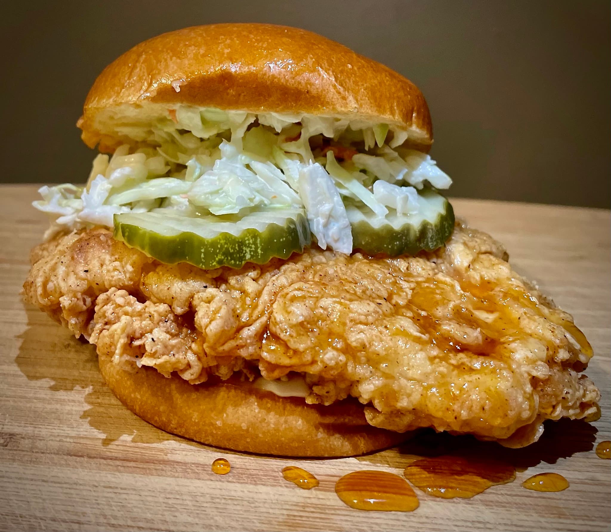Hot honey chicken sandwich with slaw and pickles on a brioche bun