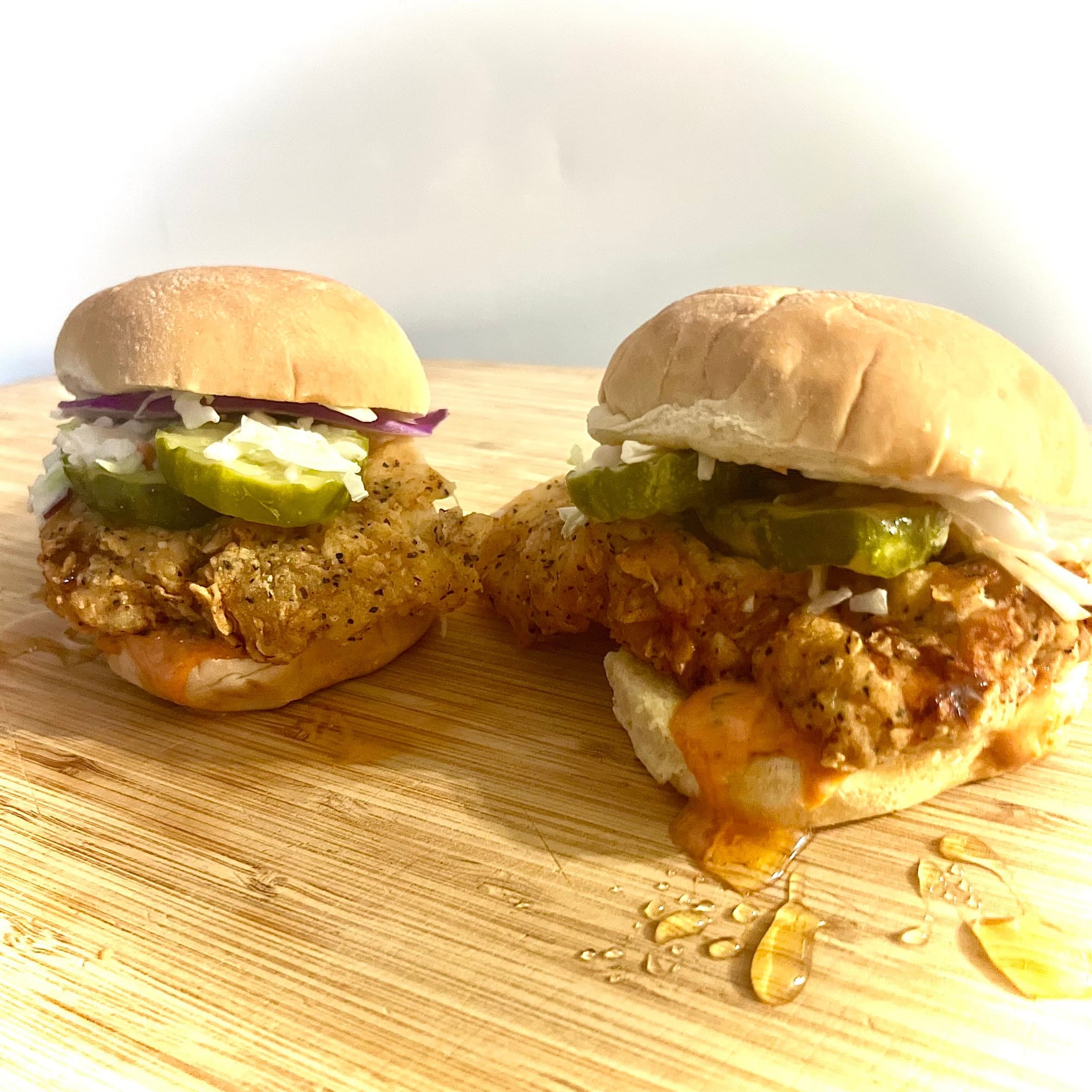 Two hot honey chicken sliders on a wooden board